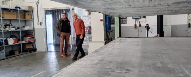 Doorkijkje door grote Burkle-pers. Op de achtergrond 2 mannen